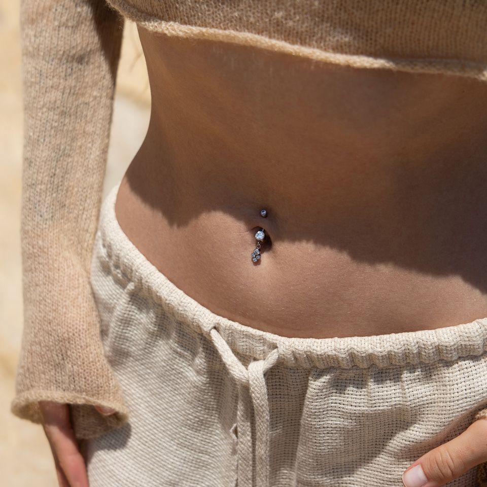 Belly button ring made of titanium with a dangling cluster of bezel-set stones